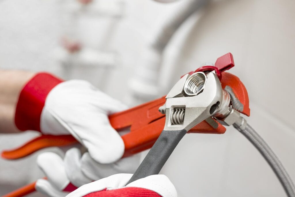 Plumber holding pipe wrenches for an emergency repair in Englewood