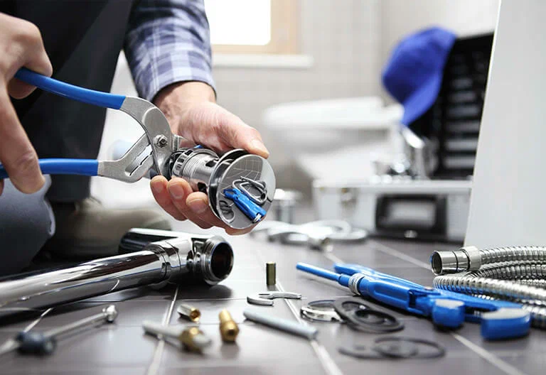 Technician repairing a plumbing fixture with professional tools in Englewood
