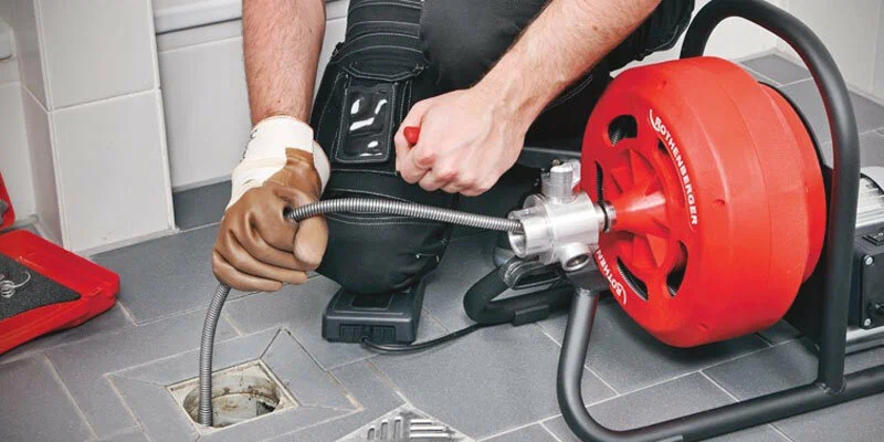 Plumber using a drain-cleaning machine in Englewood