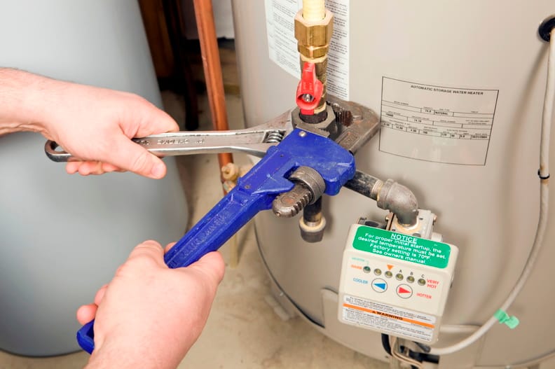 Plumber repairing a water heater valve in Englewood
